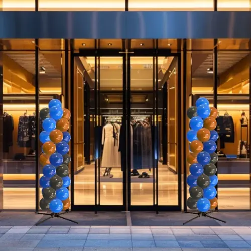 Twee van dezelfde ballonpilaren naast de verlichte entree van een modewinkel